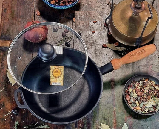 Black cast iron frying pan with wooden handle on a rustic surface with ingredients