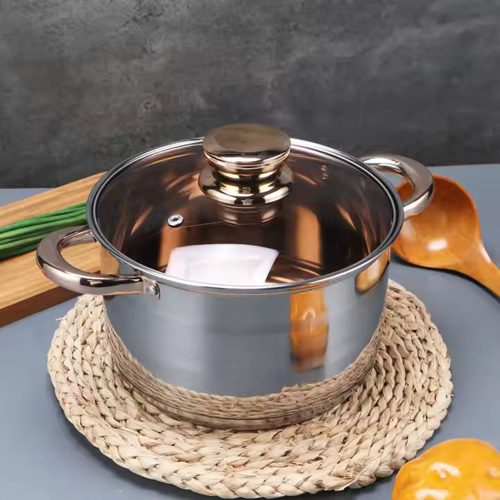 Stainless steel pot with lid on a woven mat against a gray background