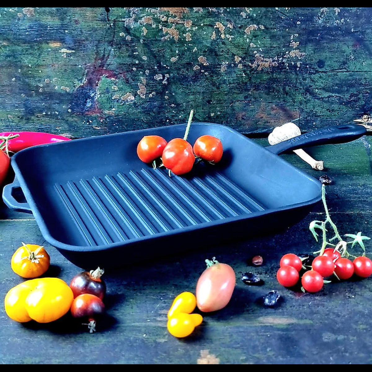 Black cast iron grill pan with vegetables on a rustic wooden surface
