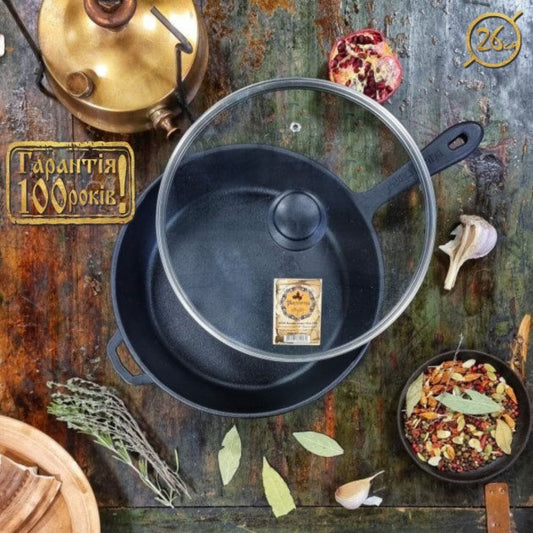 Black cast iron cookware set on a rustic wooden surface with herbs and spices.