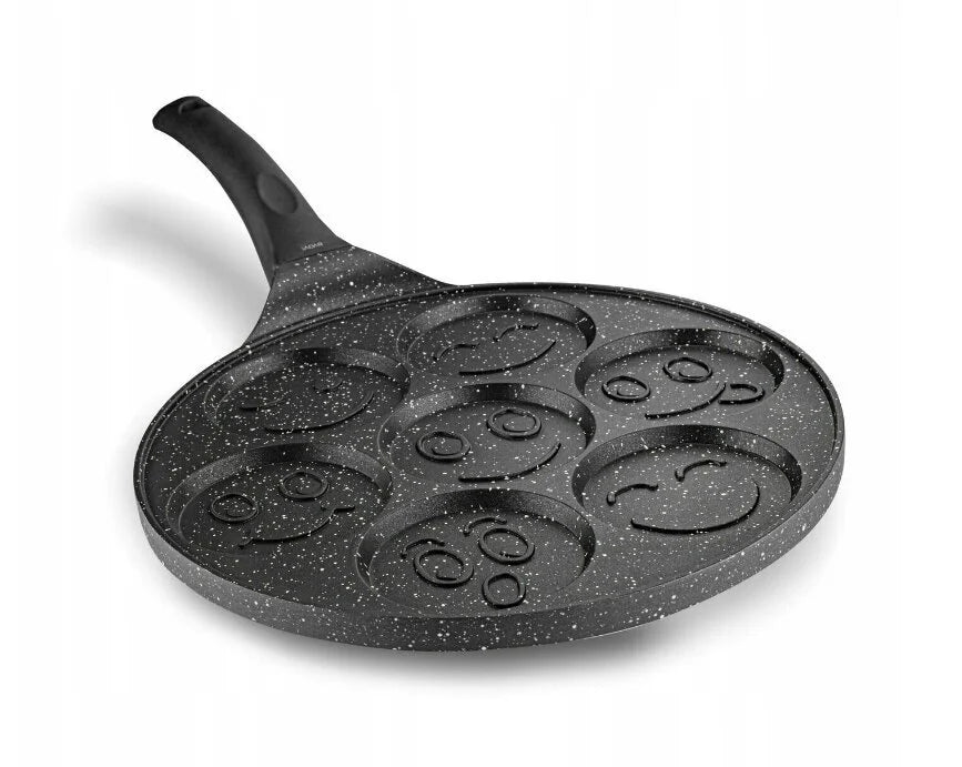 Black speckled griddle pan with smiley face designs on a white background
