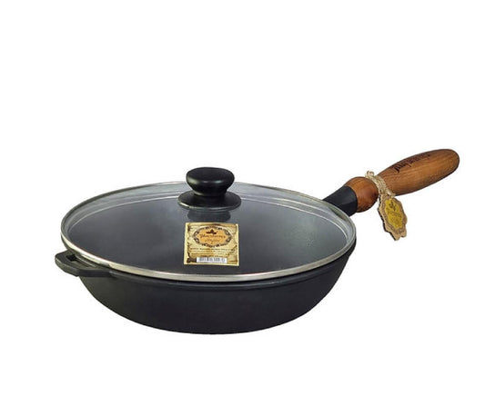Black cast iron frying pan with wooden handle and glass lid on a white background