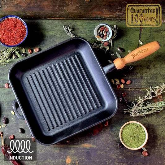 Black сast iron grill pan with wooden handle on a rustic wooden surface with spices and herbs.
