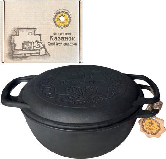 Black cast iron cauldron with decorative design on a white background, featuring a branded box.