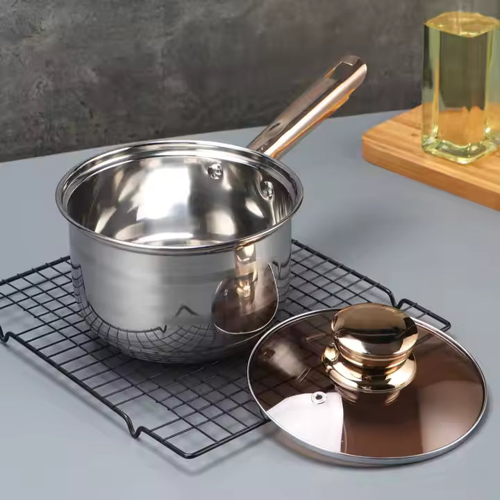 Stainless steel pot with lid on a cooling rack on a gray surface.
