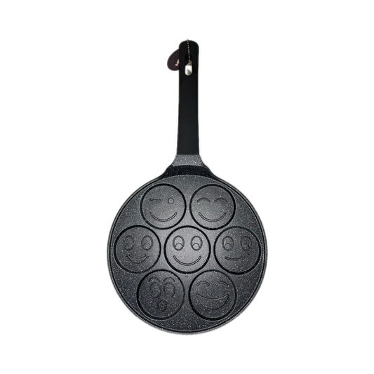 Black pancake pan with smiley face designs on a white background