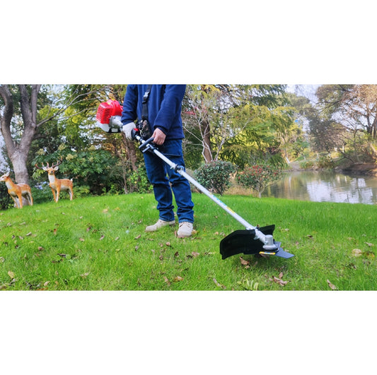 Person using a grass trimmer in a park with deer and trees in the background