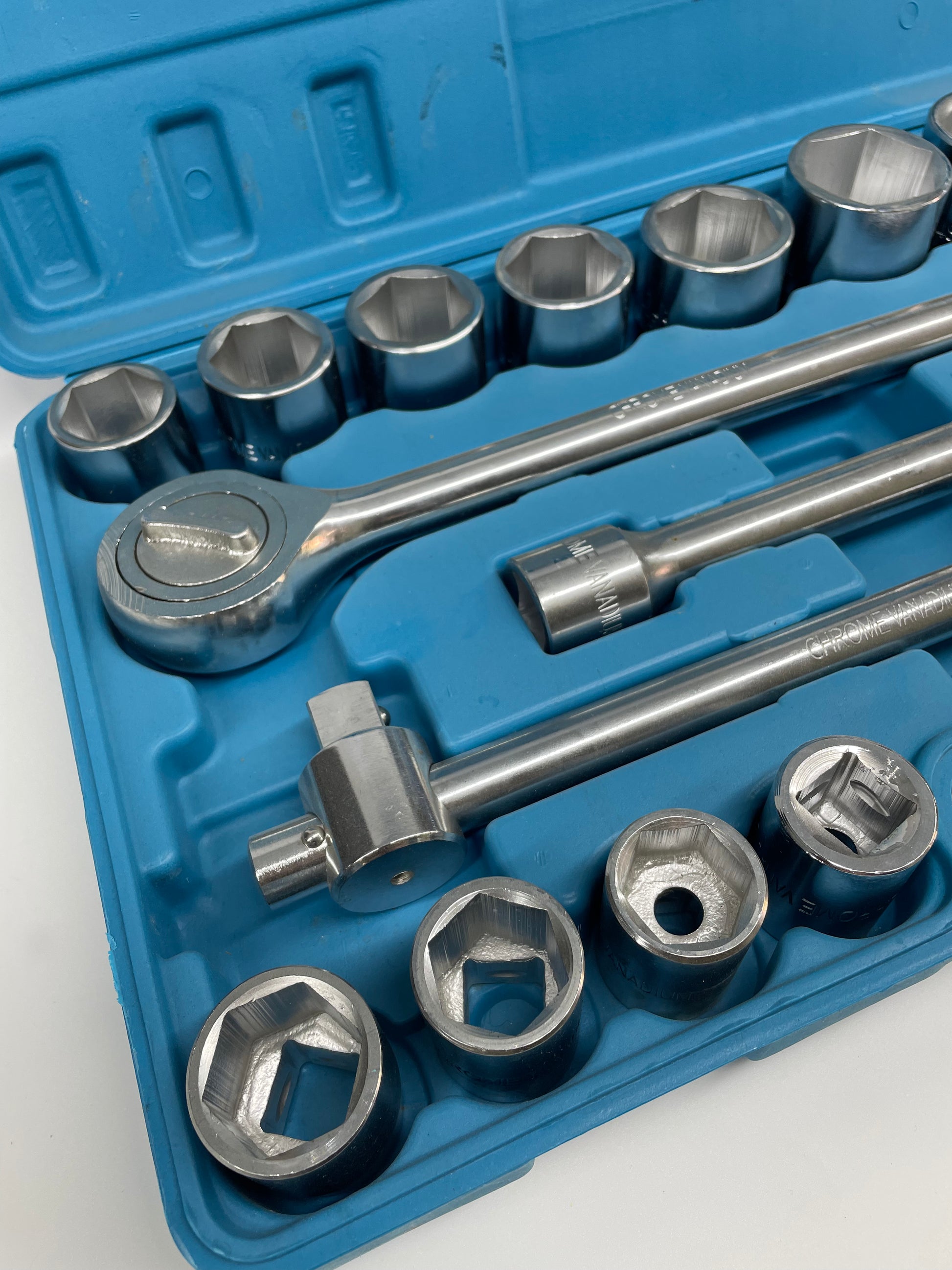 Set of sockets and wrenches in a blue tool case on a white background