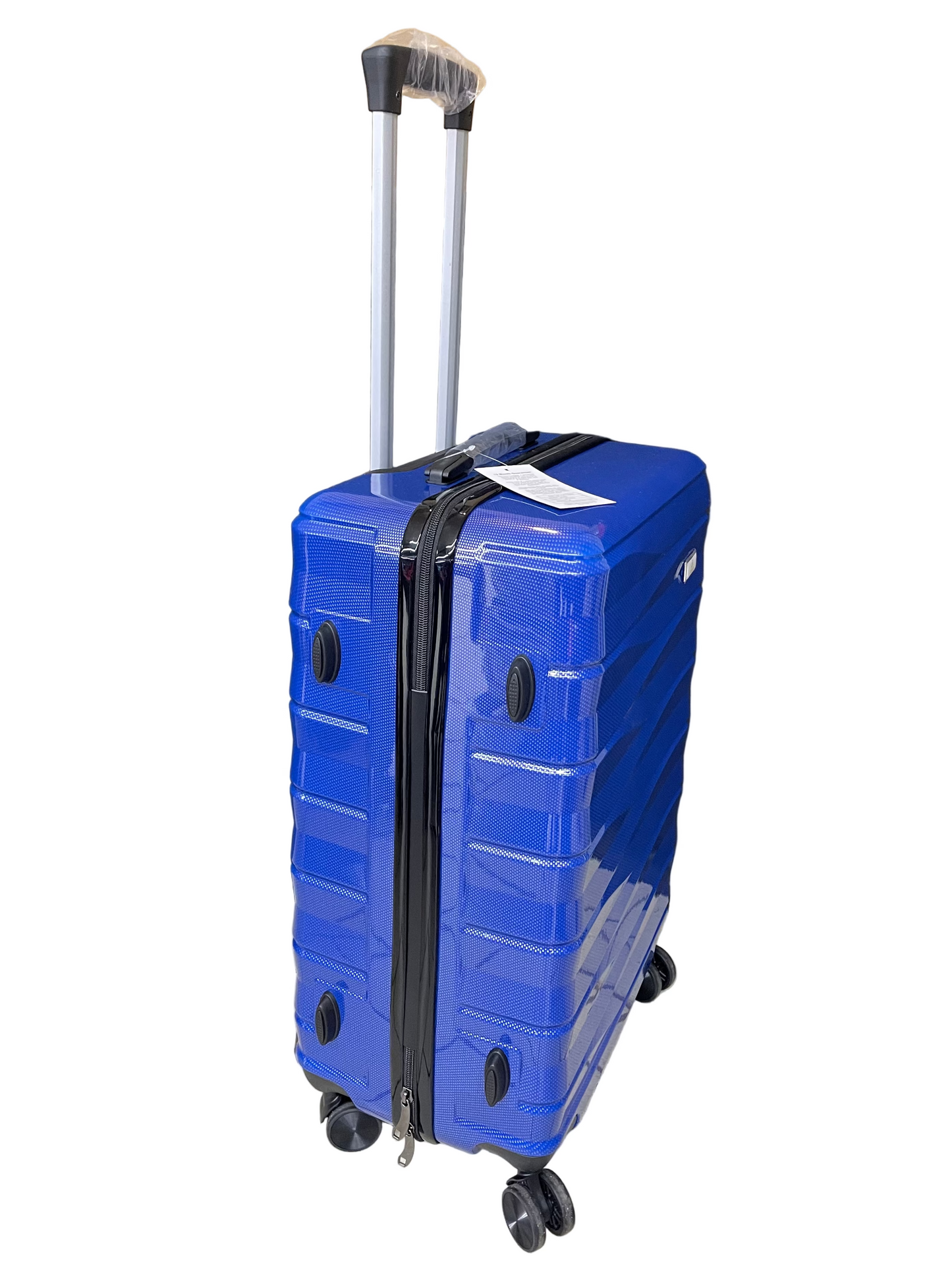 Blue suitcase with wheels on a tiled floor with a black curtain and cardboard box in the background