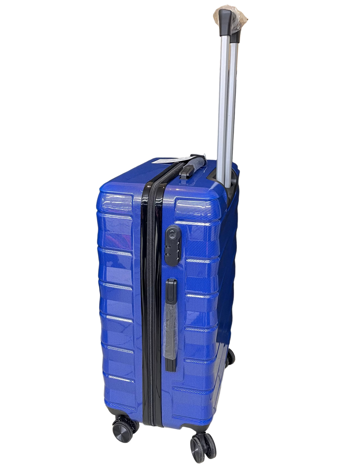 Blue suitcase on wheels in a store setting with a black curtain and cardboard boxes in the background.