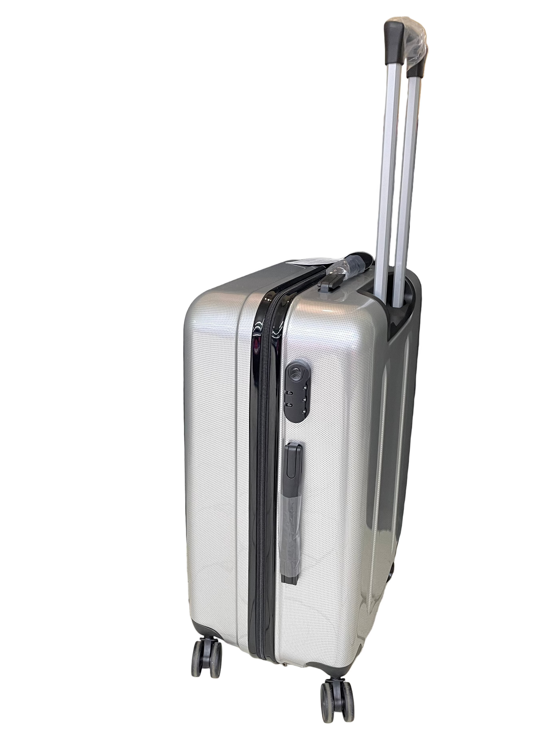Silver suitcase with wheels on a tiled floor with a black curtain and cardboard box in the background.