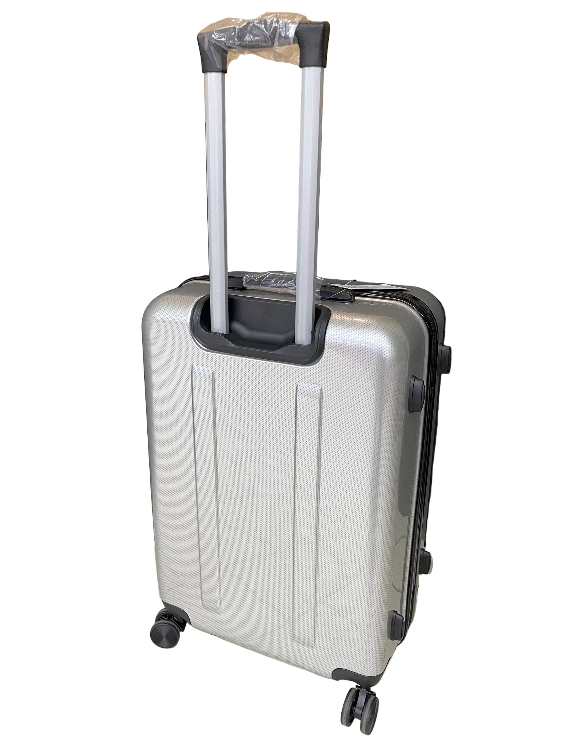 Silver suitcase with black wheels on a tiled floor with a black curtain and cardboard box in the background.