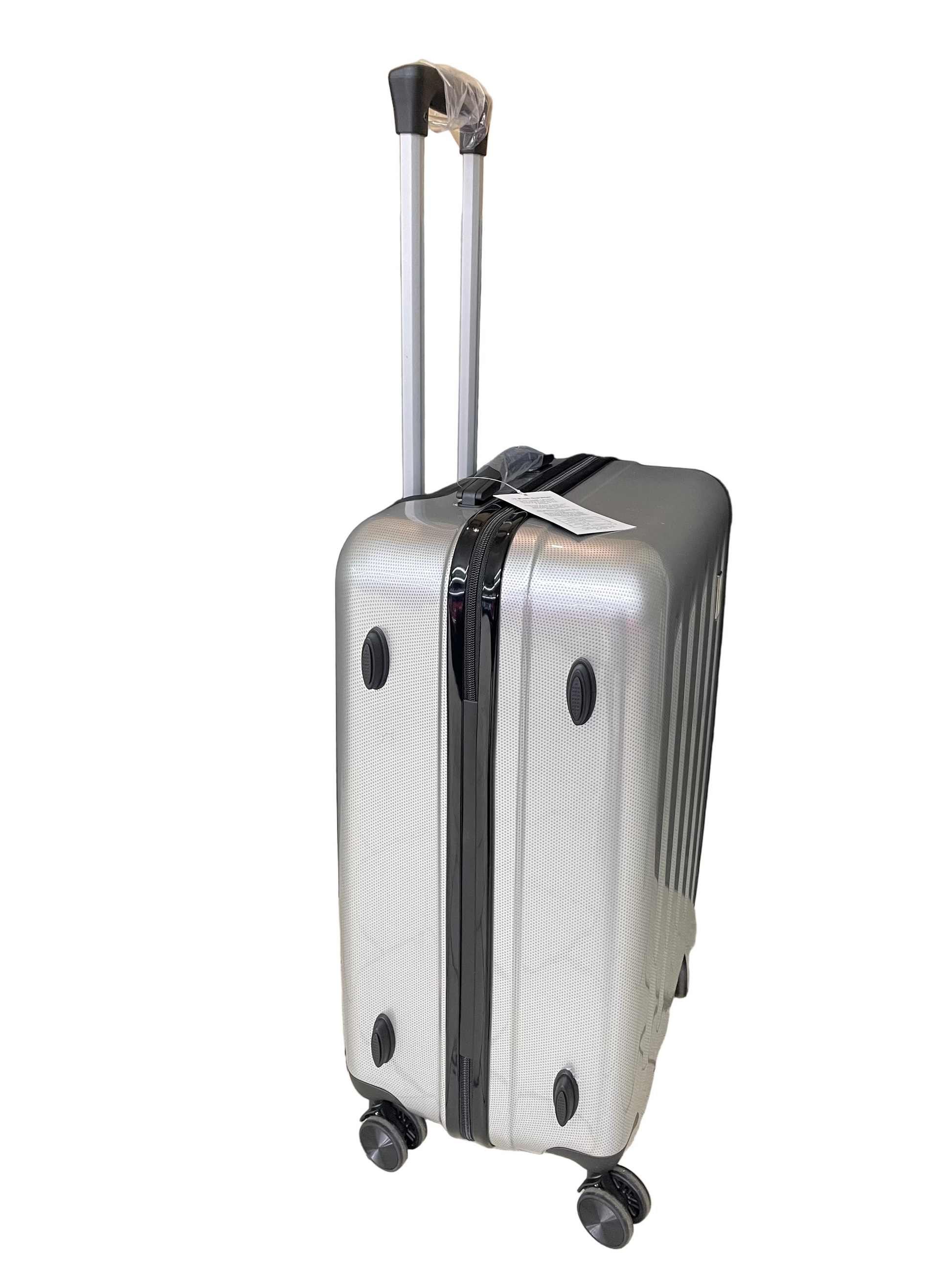 Silver suitcase with wheels on a tiled floor with a black curtain and cardboard box in the background