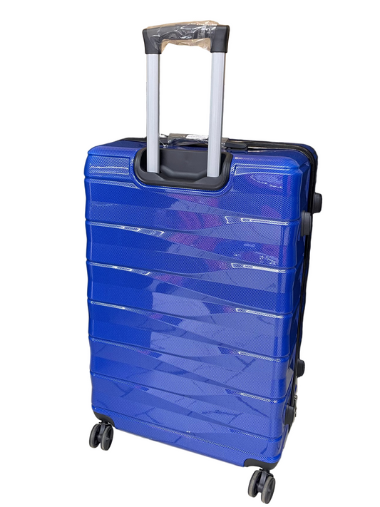 Blue suitcase with wheels on a tiled floor with a black curtain and cardboard box in the background
