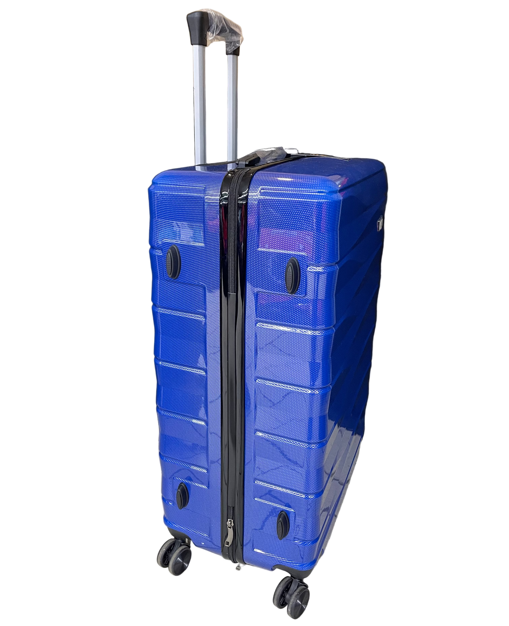 Blue suitcase with wheels on a tiled floor with a black curtain and cardboard box in the background