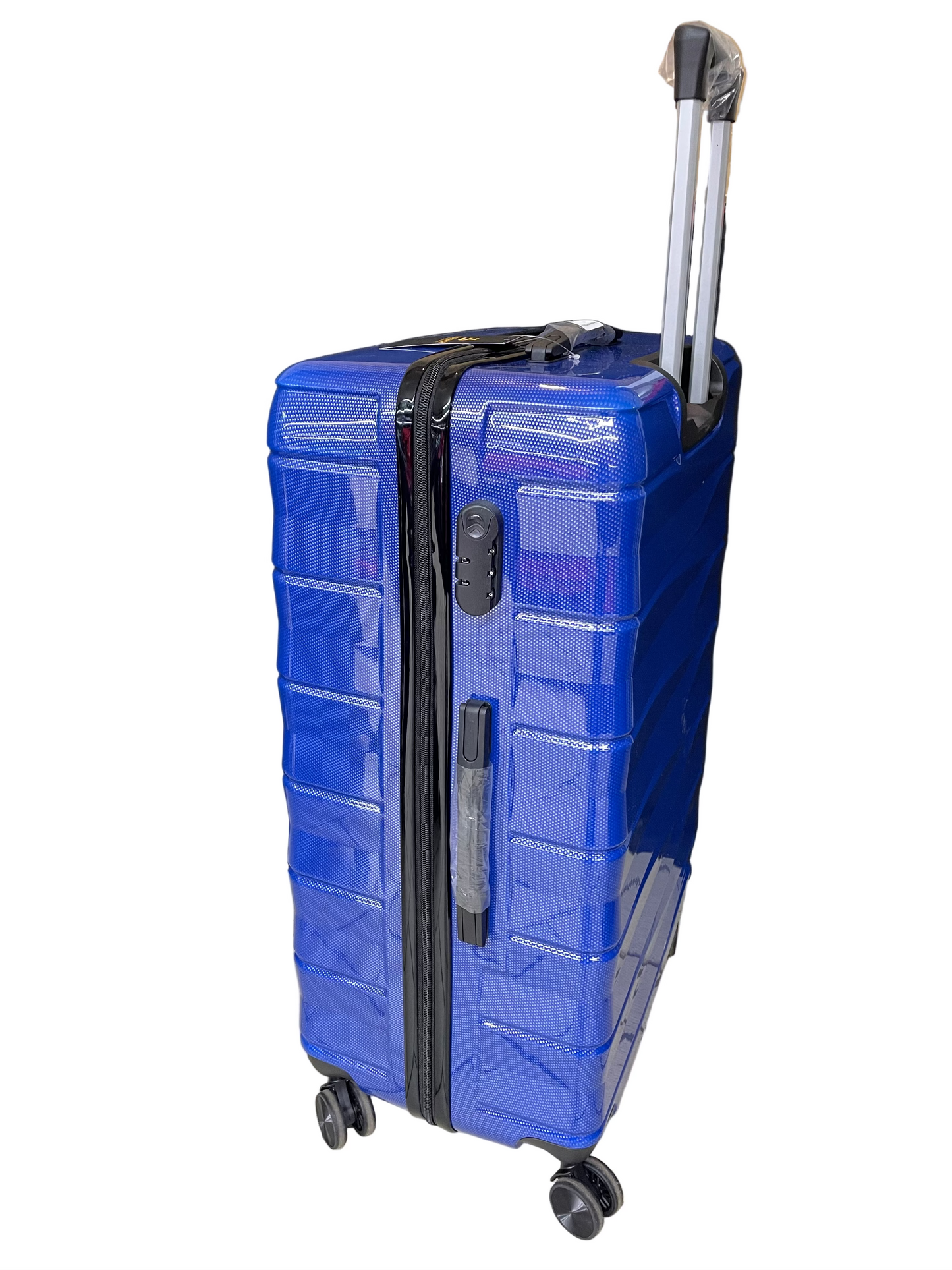 Blue suitcase with wheels on a tiled floor with a black curtain and cardboard boxes in the background