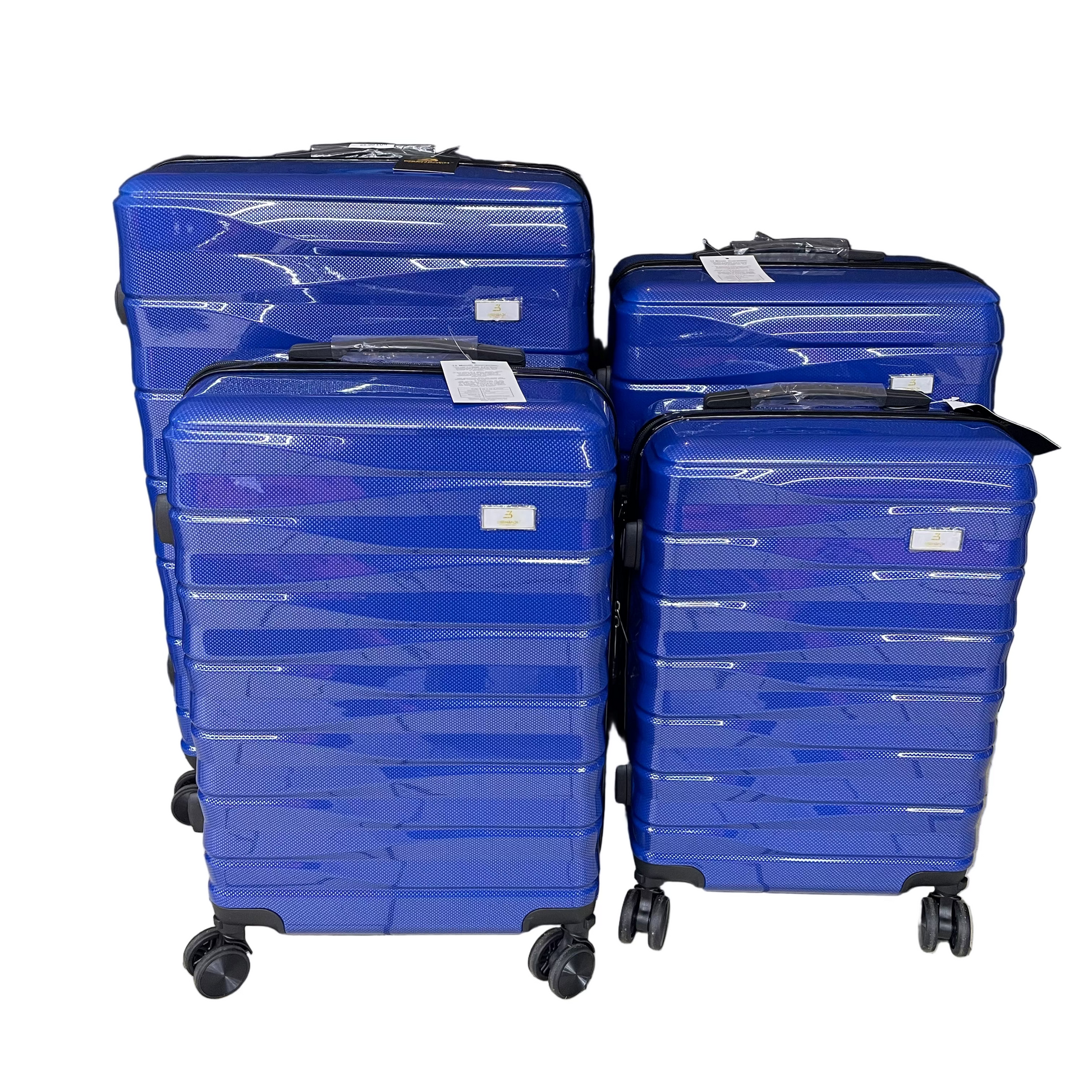 Four blue suitcases stacked on a tiled floor with a black curtain in the background.