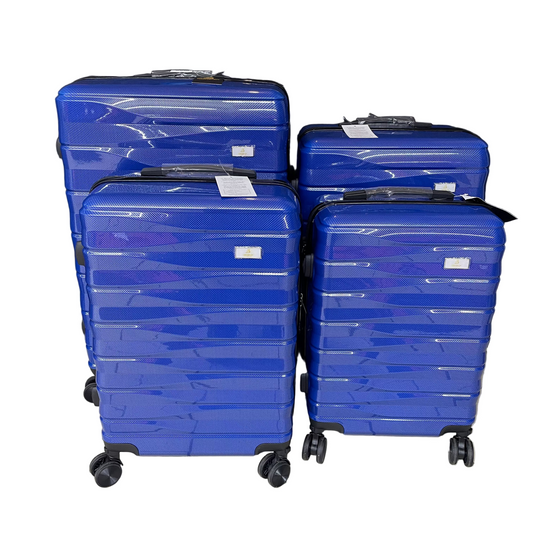Four blue suitcases stacked on a tiled floor with a black curtain in the background.