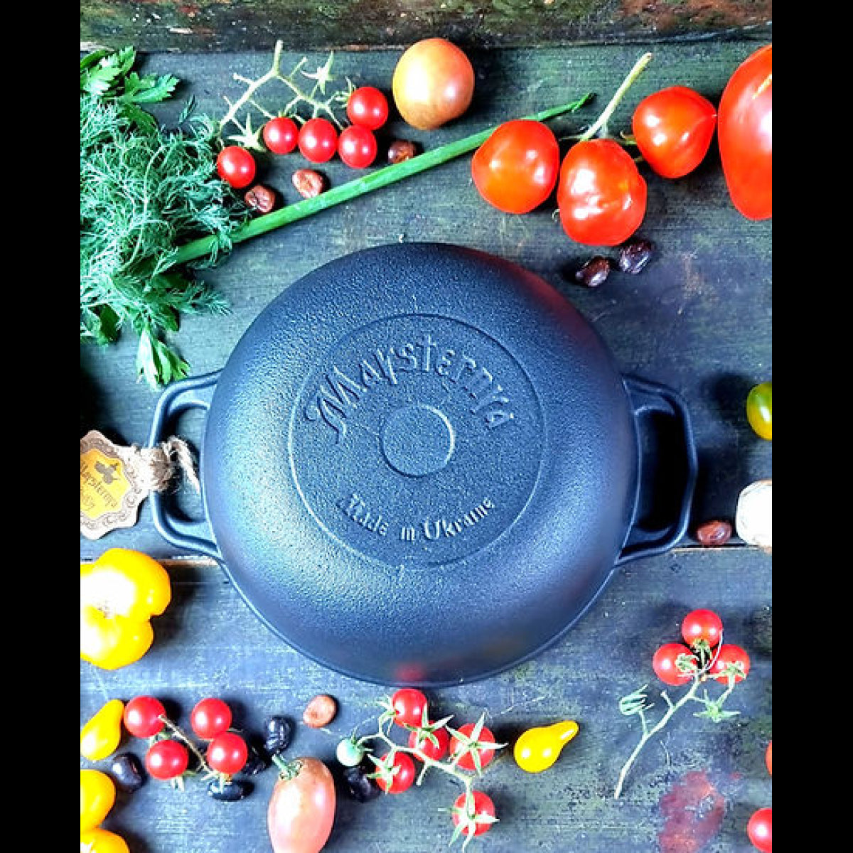 Black cast iron skillet with 'Vanderwarr' branding on a wooden surface with vegetables.