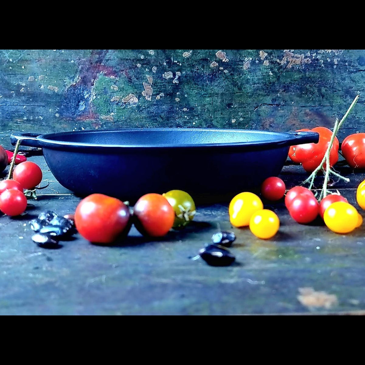 Blue bowl surrounded by red and yellow tomatoes on a textured surface