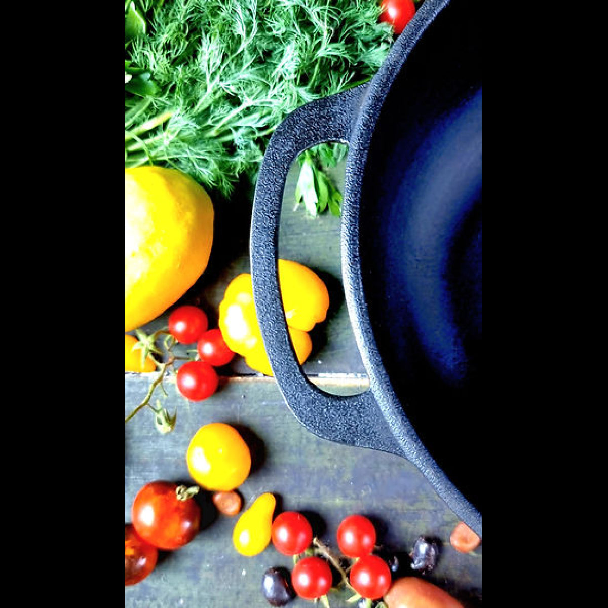 Black cast iron skillet with vegetables on a rustic background