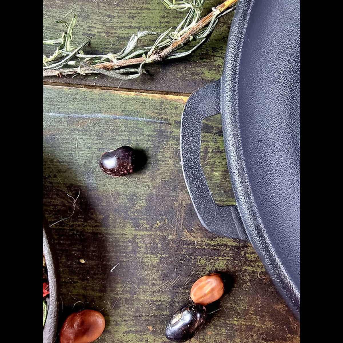Cast iron skillet on a rustic wooden surface with herbs and fruits