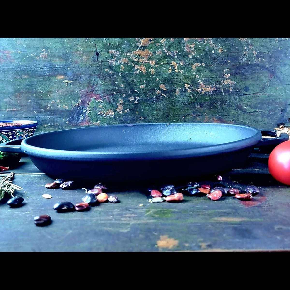 Blue ceramic dish on a textured surface with colorful stones around it.