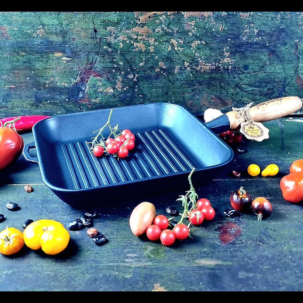 Black cast iron grill pan on a rustic wooden surface with vegetables