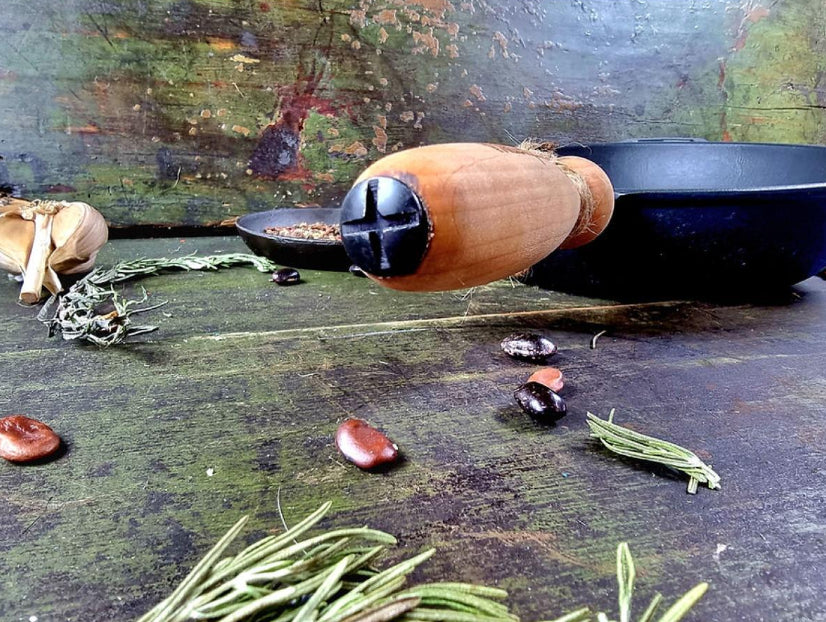 Wooden acorn with black cap on a rustic wooden surface with herbs and seeds.