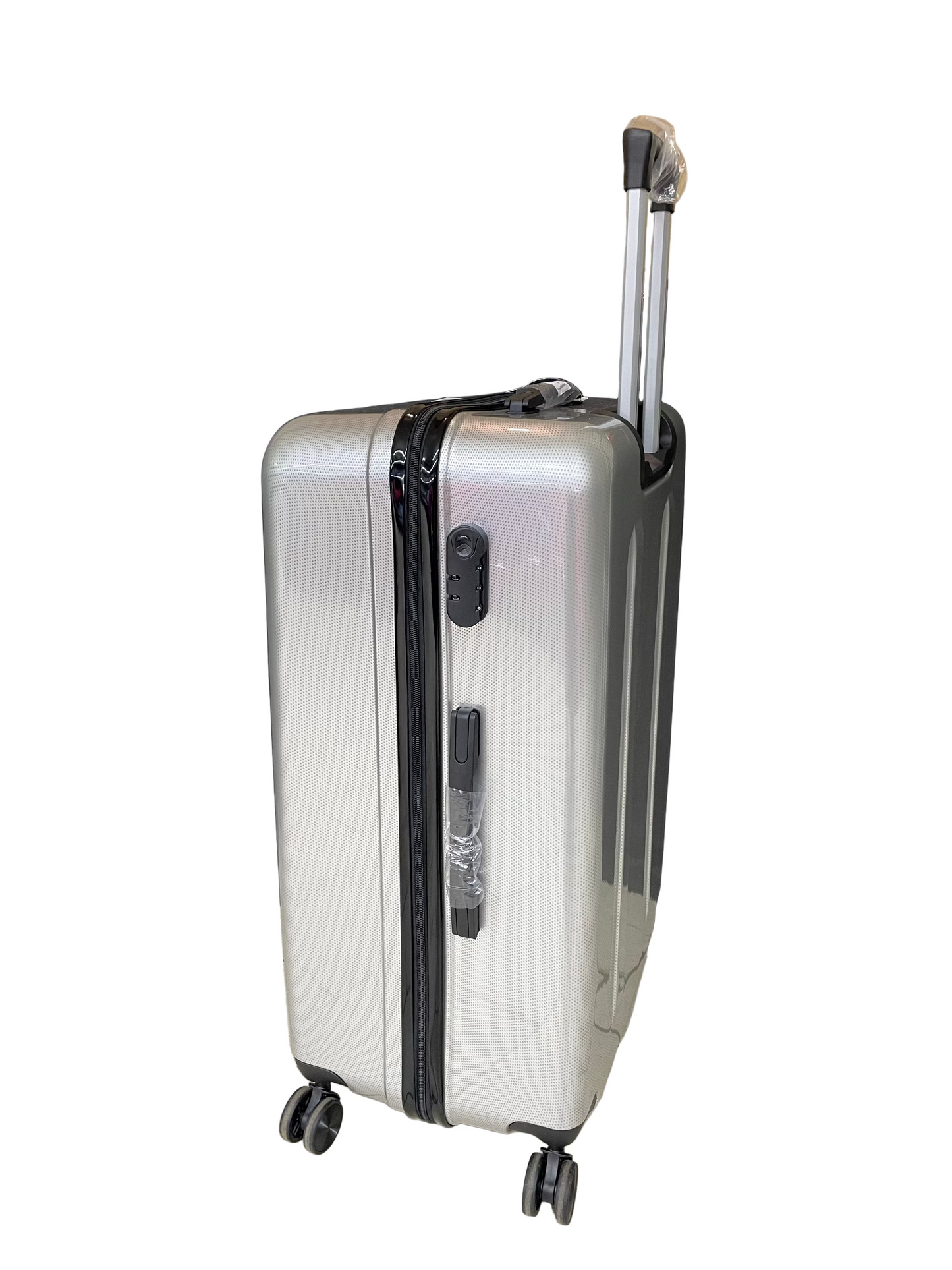 Silver suitcase with wheels on a tiled floor with a black curtain and cardboard box in the background.