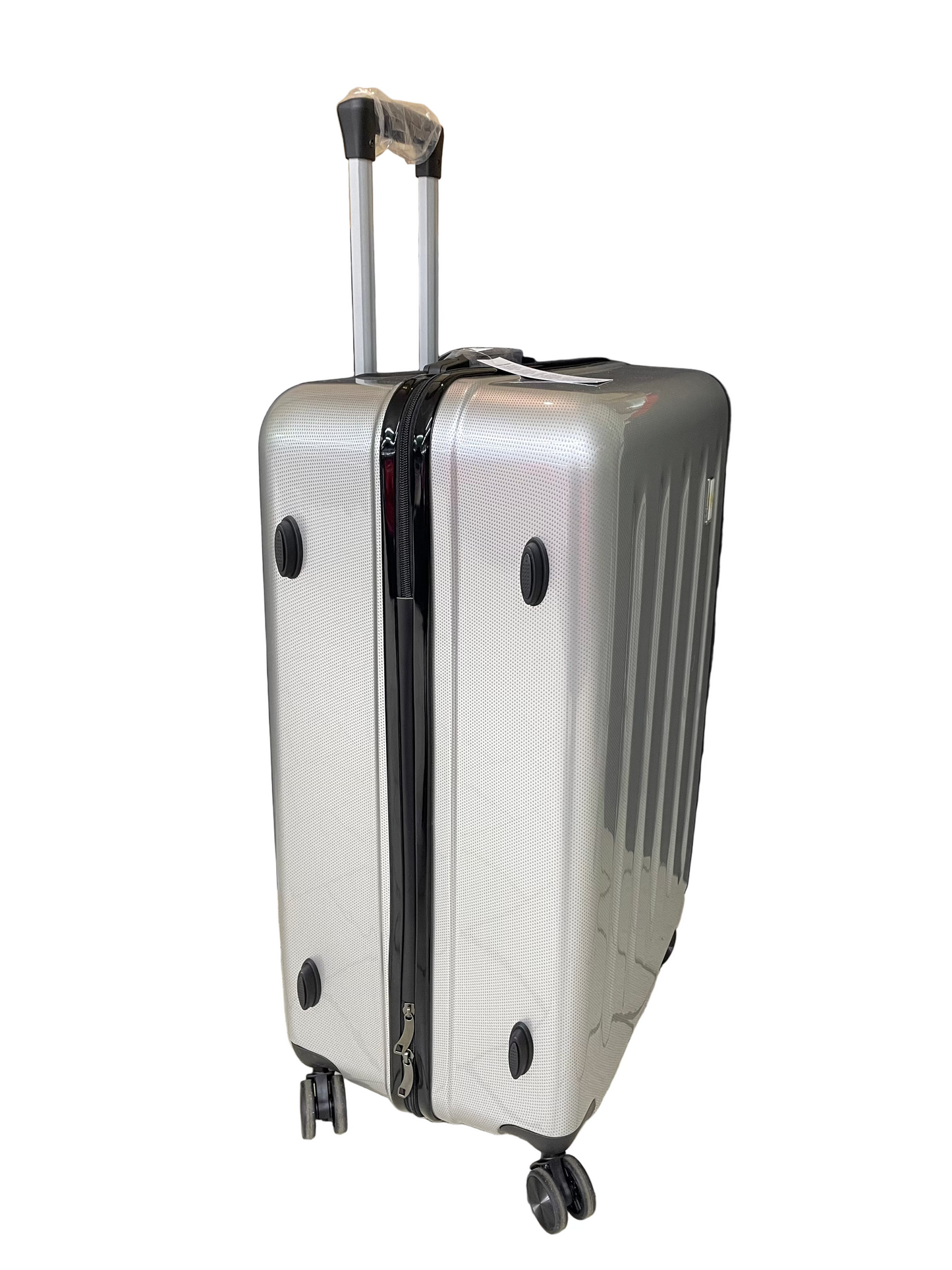 Silver suitcase with wheels on a tiled floor with a black curtain and cardboard box in the background.