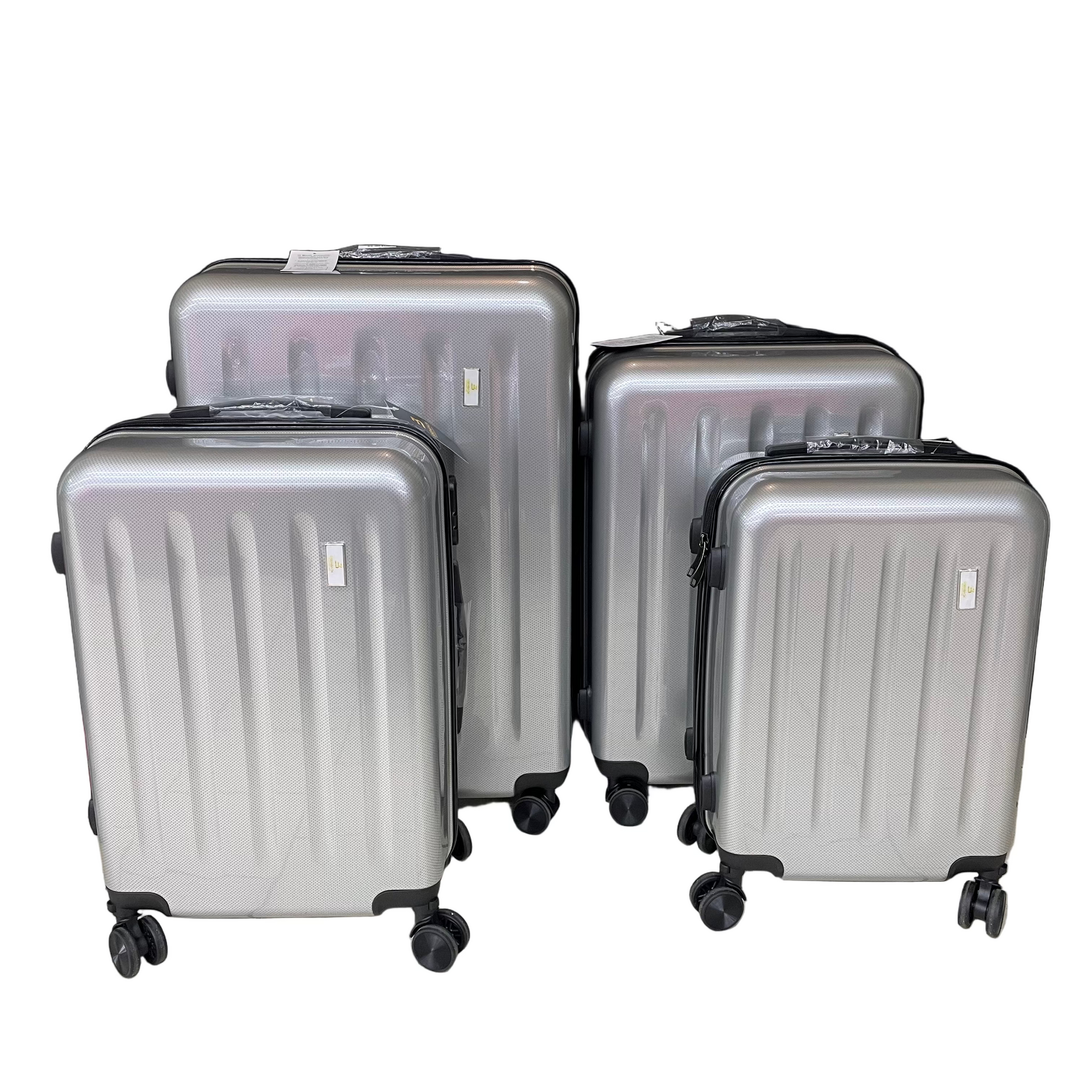 Set of silver suitcases on a tiled floor with a black backdrop
