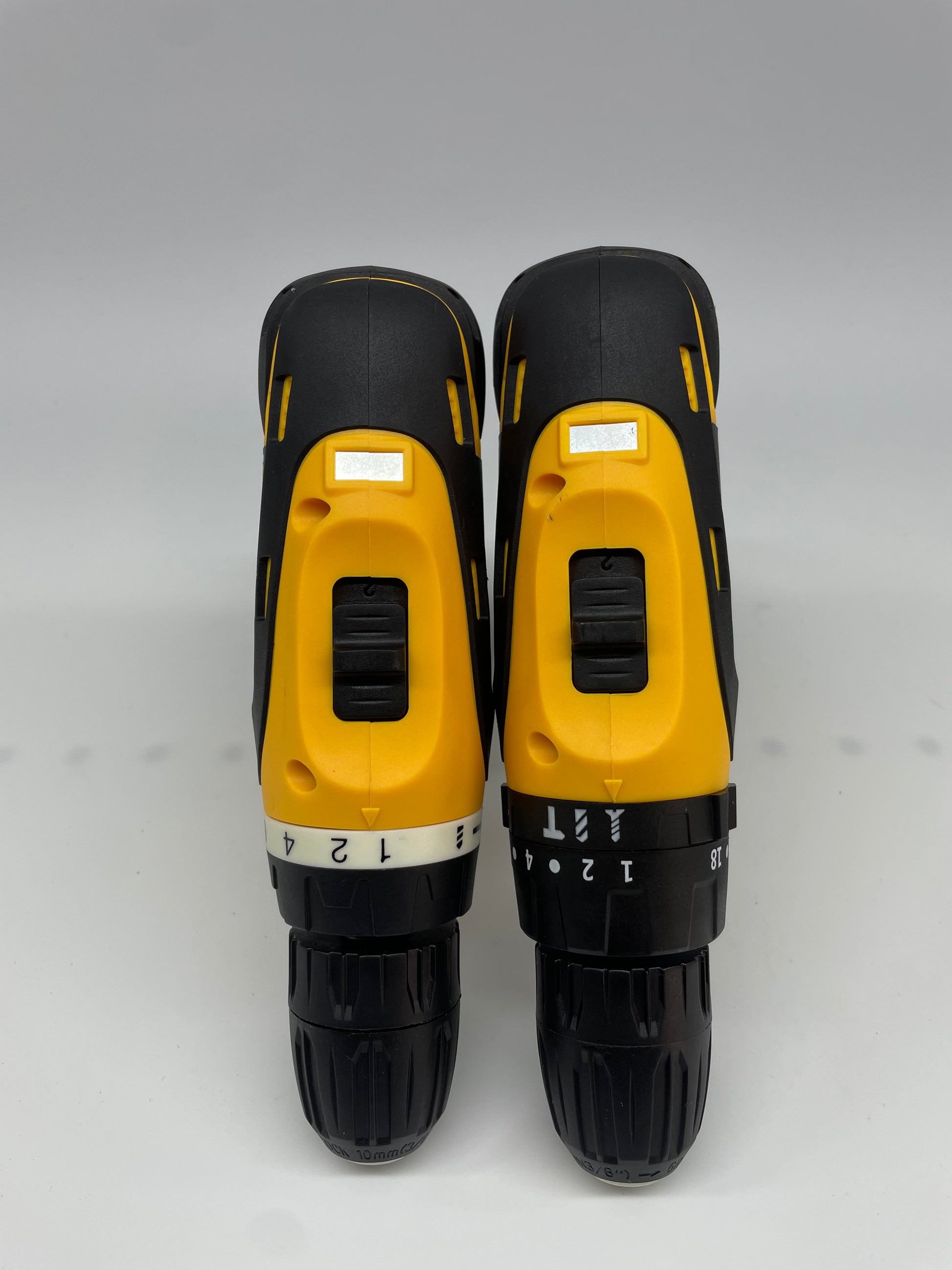Two black and yellow power drills on a gray background